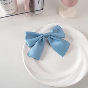 Dettaglio ravvicinato di un fiocco per capelli in raso blu su un piatto di ceramica