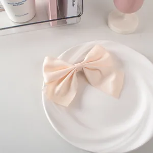 Dettaglio di un fiocco per capelli in raso color crema su un piatto bianco pulito