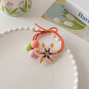 Close-up of bright orange elastic hair tie with macaron beads and floral acrylic pendant