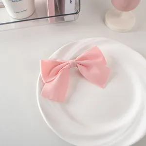 Dettaglio di un fermaglio per capelli con fiocco in raso rosa su piatto di ceramica