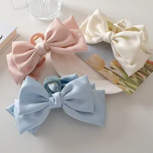 Three large satin bow hair claws in pink, cream white, and light blue silk fabric