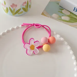 Detail of sweet floral hair tie with colorful matte beads and acrylic flower on a tray