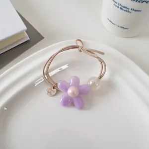 Détail de l'élastique à cheveux fleur lavande avec perle et double cordon sur un plat