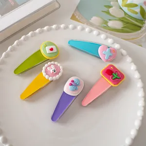 Detailopname van 5-delige cartoon haarclips in snoepkleuren op een parelplateau