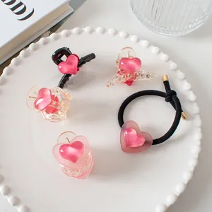Lot de 5 pinces à cheveux cœur rose et chouchou noir sur une assiette décorative