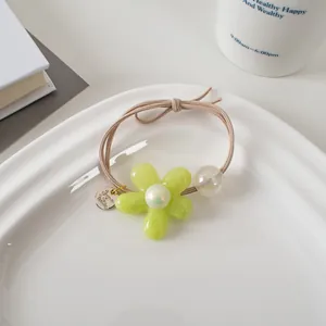 Détail d'élastique à cheveux fleur vert clair avec perle dans un plateau blanc