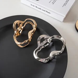 Mollette per capelli in metallo fluido minimalista color oro e argento su piatto nero
