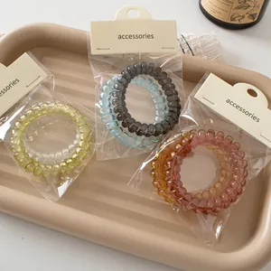 Three pairs of elegant spiral hair ties in transparent colors on cream packaging cards
