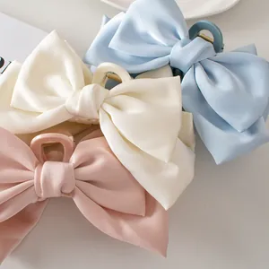 Three elegant satin bow hair claws in pink, cream, and blue colors for women's styling