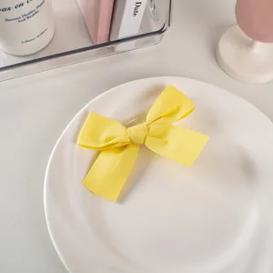 Dettaglio del fermaglio per capelli a fiocco giallo in cotone e lino su piatto