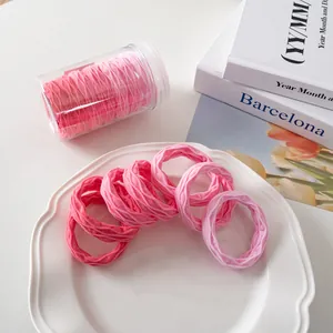 Detailansicht von 7 elastischen Haargummis mit rosa Farbverlauf in einer Vorratsdose