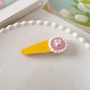 Detail van gele haarklem met roze konijn charm op een parelachtig dienblad