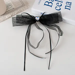 Détail de la pince à cheveux noeud en tulle noir avec cristal coeur et longs rubans