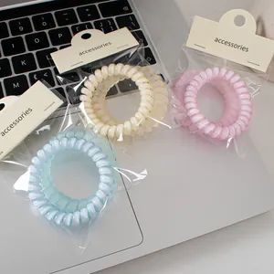 Tres gomas de pelo en espiral color gelatina azul, crema y rosa con embalaje