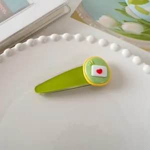 Detailopname van een schattige groene eendenbek haarclip met hart envelop motief op een bord