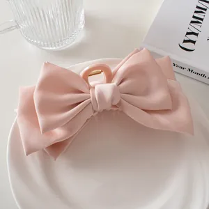 Close-up of pink satin multi-layer bow hair claw clip on a decorative white tray