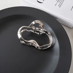 Dettaglio di un fermaglio per capelli in metallo argento ondulato su un piatto nero