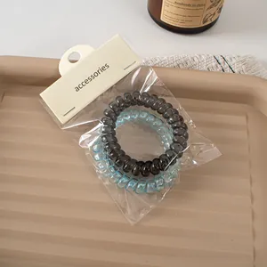 Close-up of translucent spiral hair ties in black and blue on a textured tray