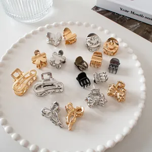 Assorted mini metal hair claw clips in heart and flower shapes displayed on a white tray