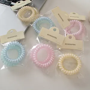 Vista detallada de gomas de pelo en espiral mate pastel con tarjeta de accesorios