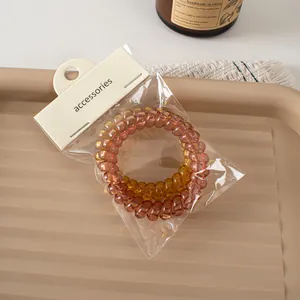 Detail of two-piece spiral hair ties in amber and brown on a beige textured tray