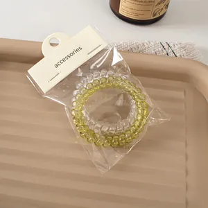 Close-up of clear and light green spiral hair ties on a tray with accessories packaging