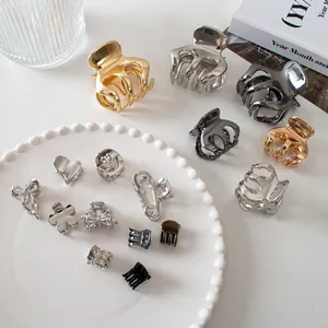 Detailed close-up of mixed metal hair claws in gold, silver and matte black on white tray