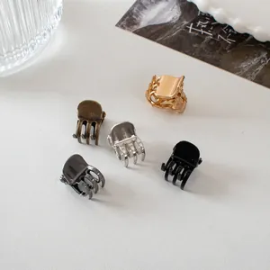 Close-up of five color mini metal hair claws including gold and silver on a white tray