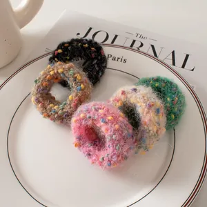 Gros plan de cinq élastiques à cheveux en tricot à pois disposés sur une assiette blanche
