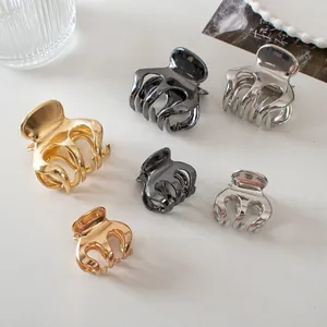 Close-up of metallic claw clips in gold, silver, and gunmetal on a minimalist background