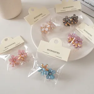 Dettaglio di mini mollette per capelli a fiore con strass e clip in metallo dorato