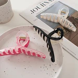 Trois grandes pinces à cheveux bicolores rose, noir et beige sur un plateau chic