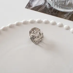 Detailed macro view of a silver metal mini hair claw clip with hollow smiley face design