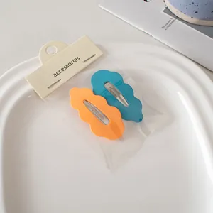 Detail süßer bonbonfarbener Wellen-Haarspangen in Orange und Blau mit mattem Finish
