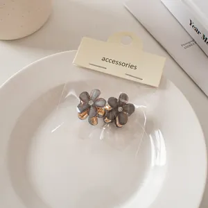 Dettaglio di mini mollette per capelli a fiori con petali traslucidi e glitter fini