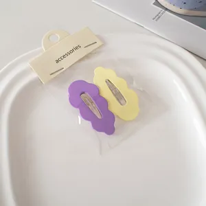Detail von matten Wellen-Haarspangen in Violett und Gelb auf weißem Keramiktablett