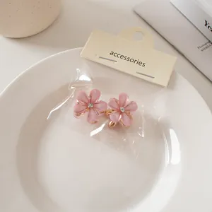 Dettaglio di mini mollette per capelli a fiore rosa opaco con piccolo strass centrale