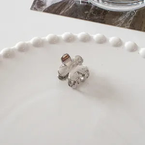 Detailed close-up of a mini silver metal flower hair claw clip on a decorative ceramic tray
