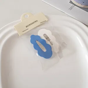 Detailansicht welliger Haarklammern in Blau und Weiß auf einer minimalistischen Karte