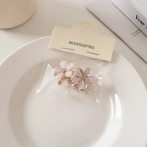 Dettaglio di mini mollette a fiore con petali opachi, cristalli e base in metallo
