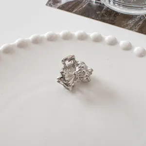 Close-up of a mini silver metal bow hair claw clip on a decorative pearl plate