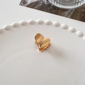 Macro shot of a mini heart-shaped metal hair claw clip with a polished gold finish