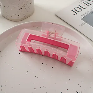 Gros plan d'une pince à cheveux rectangulaire rose à double couche sur un plateau chic