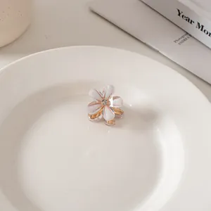 Dettaglio macro di mini molletta per capelli a fiore con petali perlati e cristallo