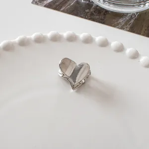 Detailed close-up of a heart-shaped silver metal hair claw clip on a pearl-edged white plate
