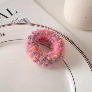 Gros plan d'un chouchou en peluche rose à pois colorés sur une assiette en céramique