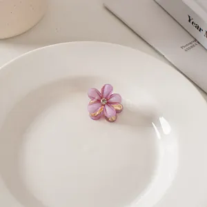 Dettaglio molletta per capelli a fiore viola con petali lucidi e strass centrale