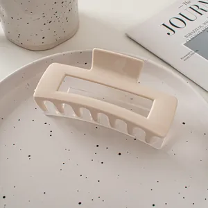 Détail d'une pince à cheveux rectangulaire beige posée sur une assiette en céramique