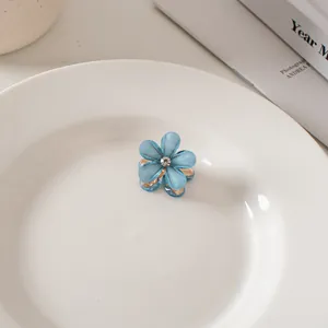 Dettaglio di una mini pinza per capelli a fiore blu con petali in resina e strass centrale