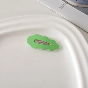 Detailaufnahme der wellenförmigen grünen Haarspange auf einem weißen Keramiktablett